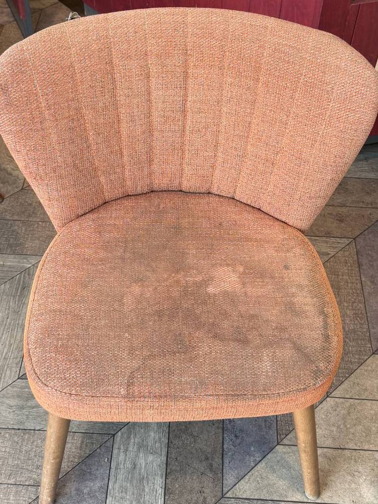 A terracotta coffee shop chair before cleaning, the seat pad greyed and patchy from daily use