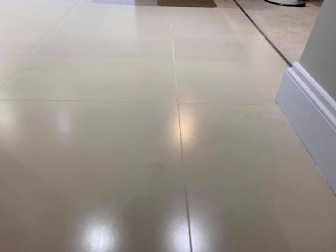 A porcelain kitchen floor with discoloured grout before cleaning