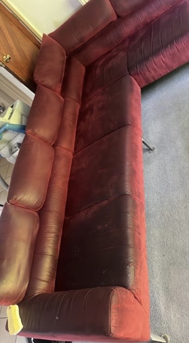 A red corner sofa before cleaning — dull and grubby