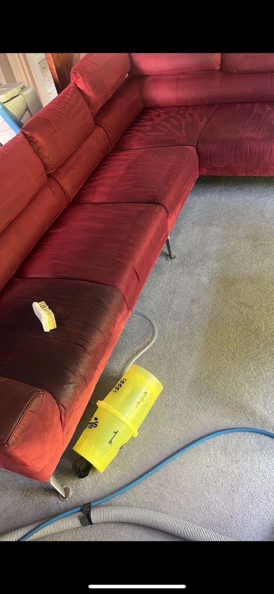 The same red sofa during cleaning — half brushed and hot-water extracted