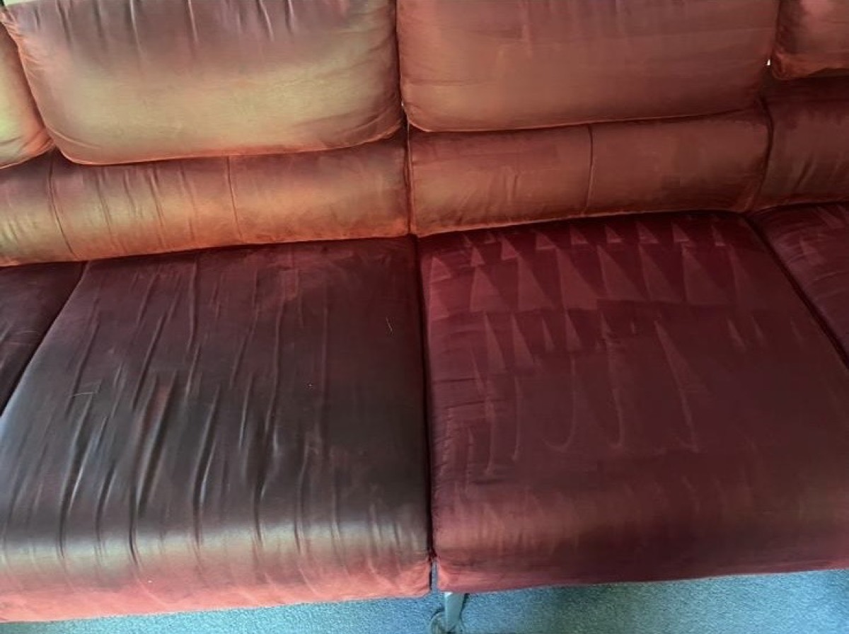 A red velvet sofa mid-clean — the right cushion refreshed, the left still to do