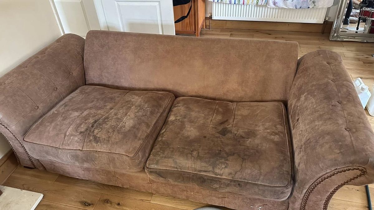 The same brown sofa before cleaning — heavily stained seat cushions